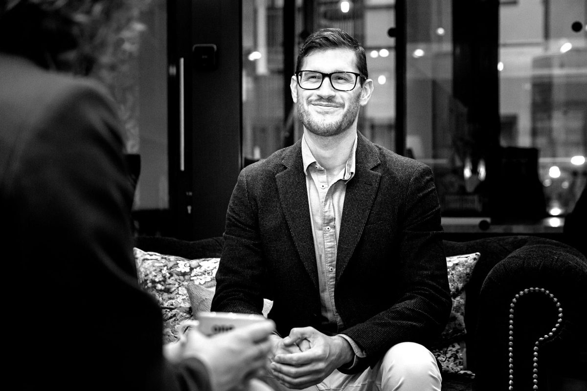 Santiago in conversation across a table, black and white